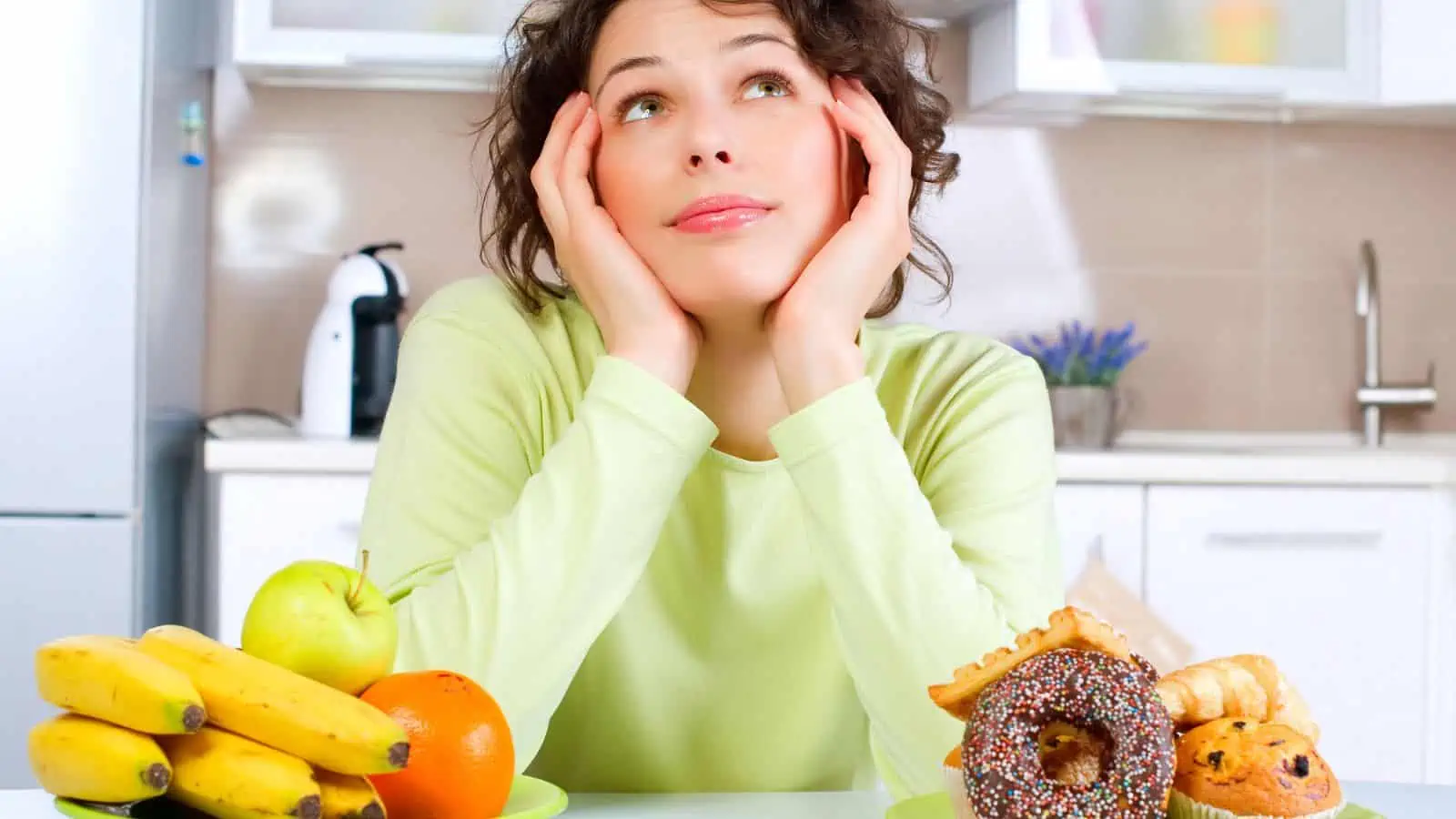 woman choosing between plate of fruit and plate of donuts and muffins