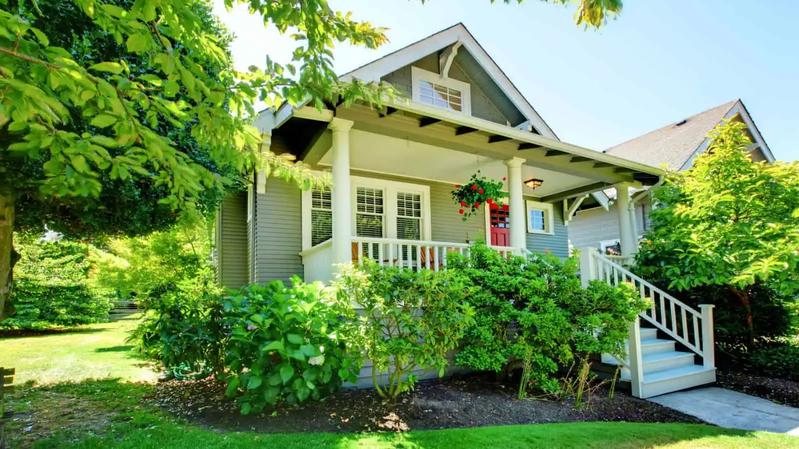 craftsman style house with green bushes and red front door