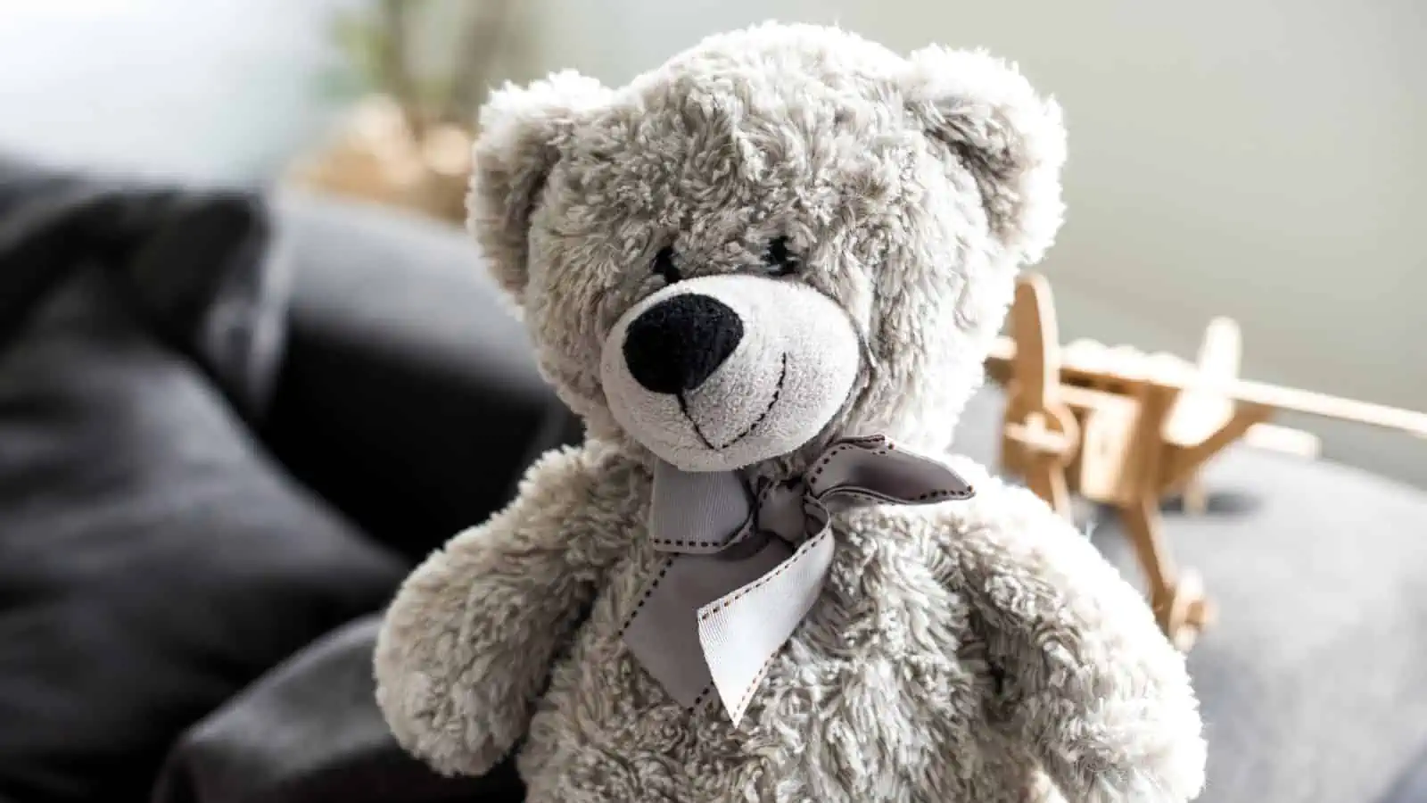 gray teddy bear with bow around neck