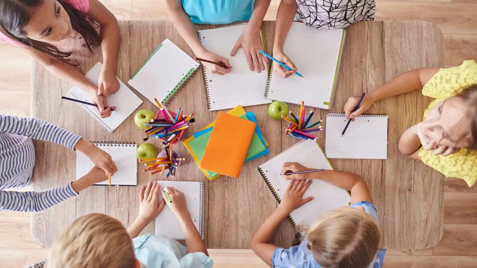 children standing around table with notebooks and school supplies