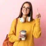 happy woman in glasses holding coffee and pointing up