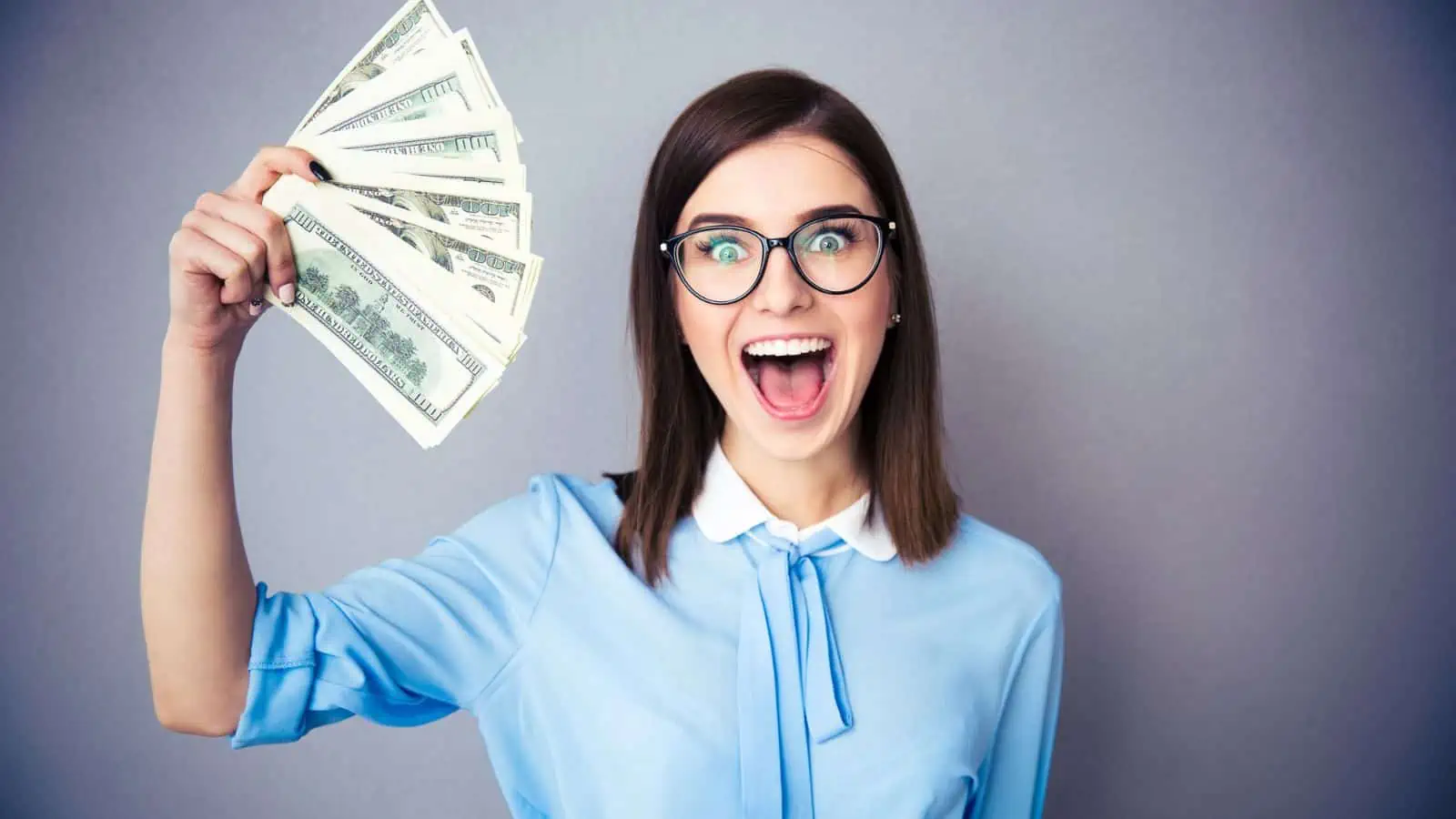 smiling woman holding fan of 100 dollar bills