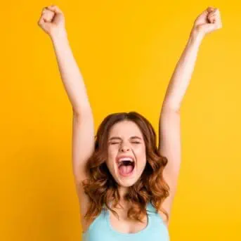 woman celebrating with arms in air yellow background