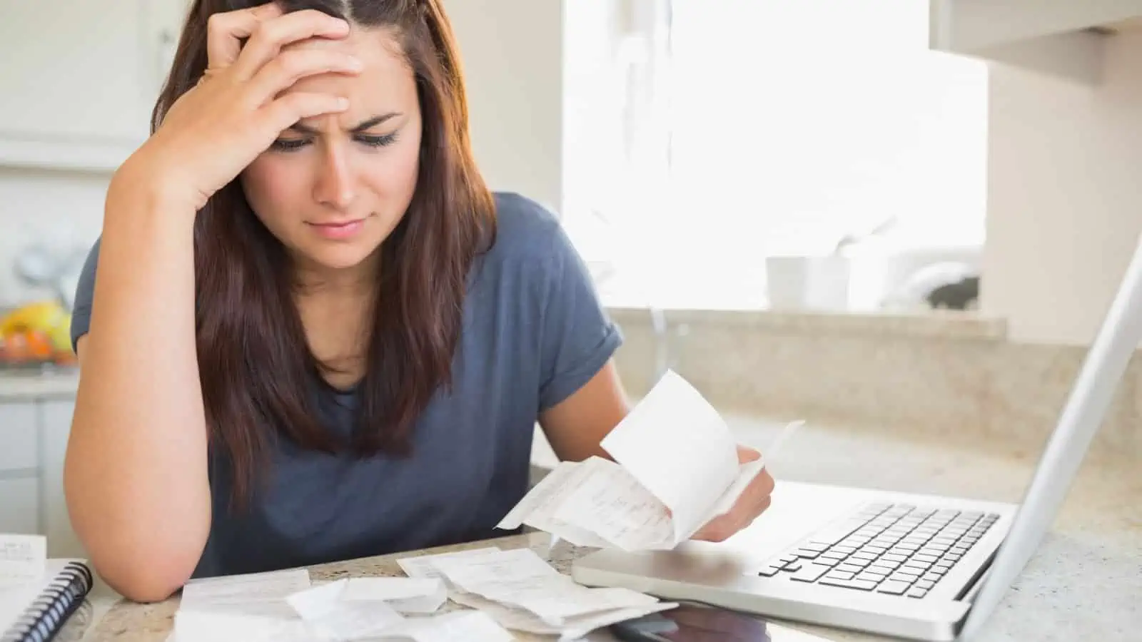 woman holding receipts with head on hand looking stressed