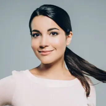 woman smiling and touching her own hair in ponytail