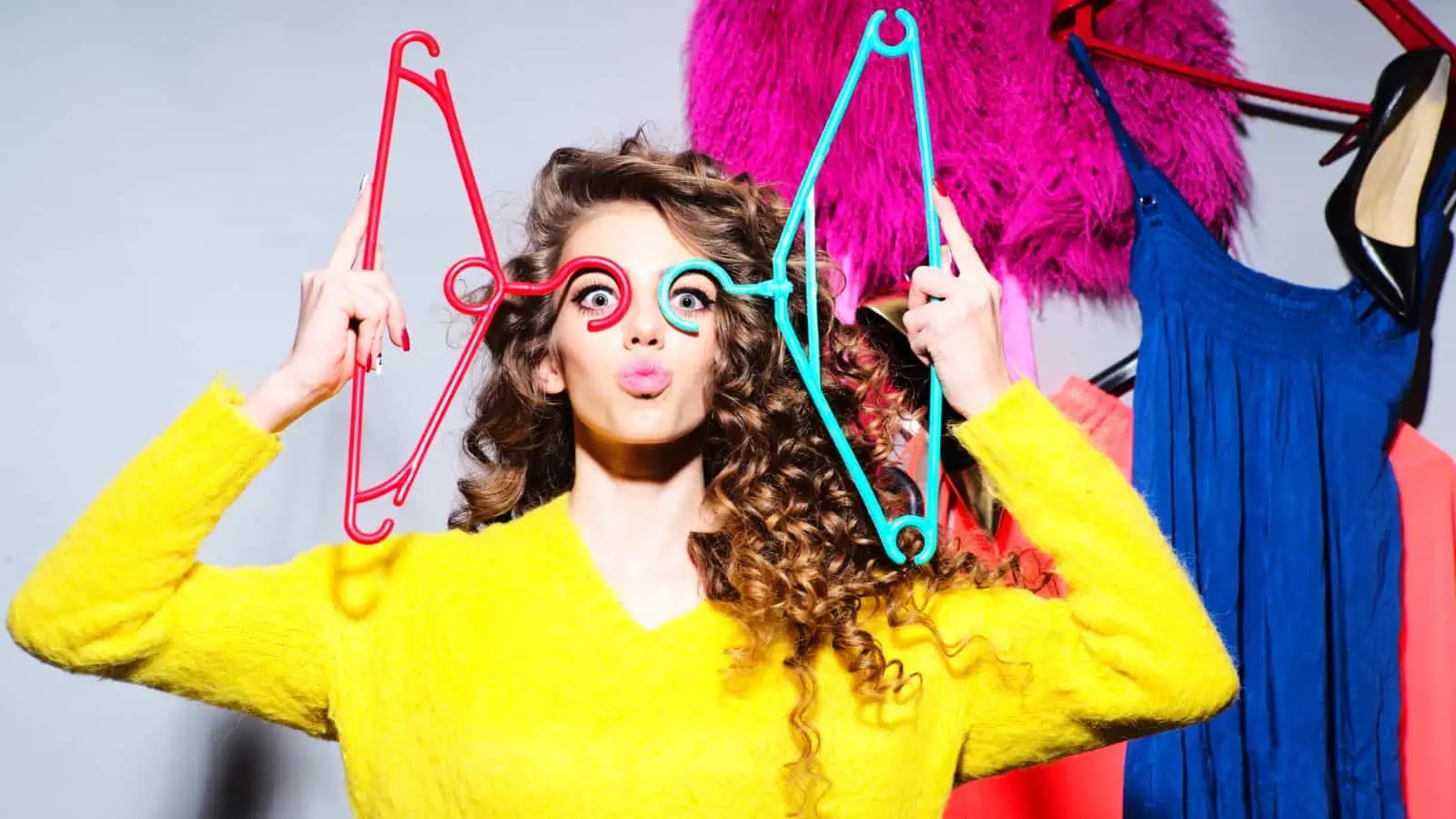 woman sticking lips out and holding hangers to her eyes