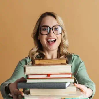 woman wearing glasses and holding a stack of books