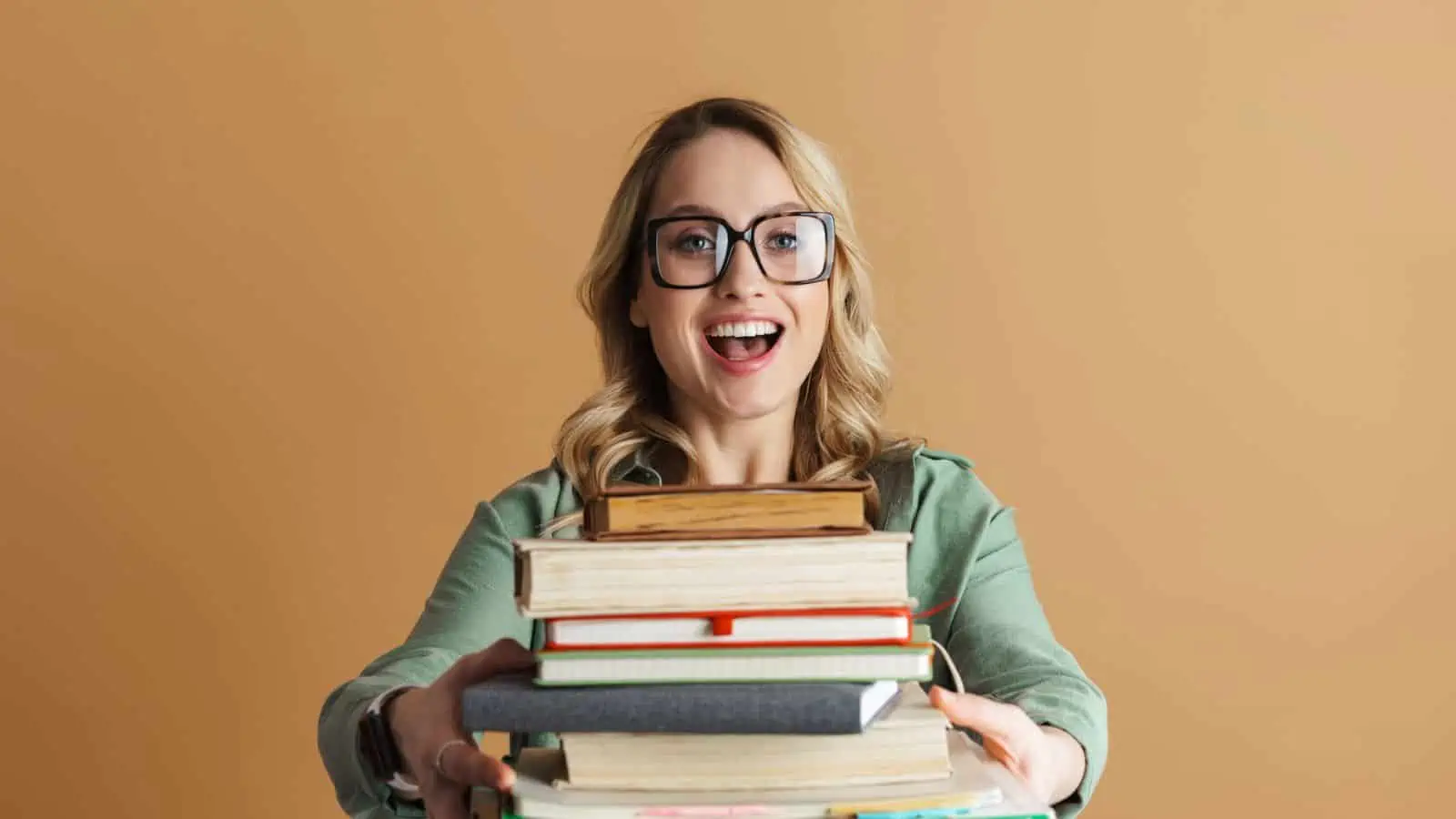 woman wearing glasses and holding a stack of books