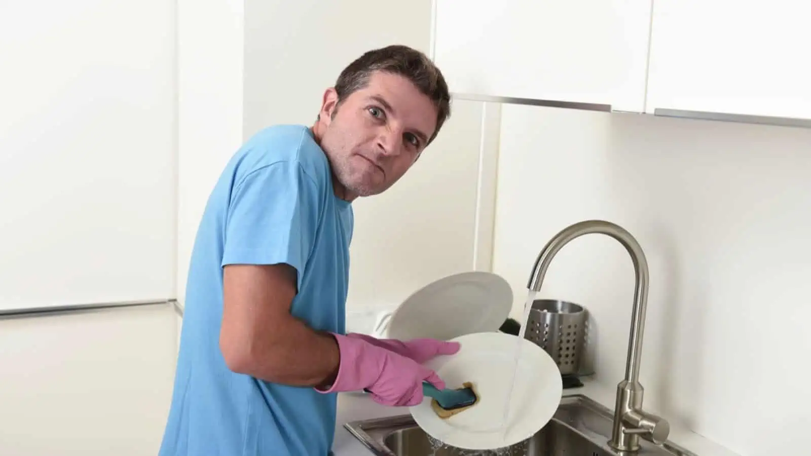 Man cleaning dishes annoyed