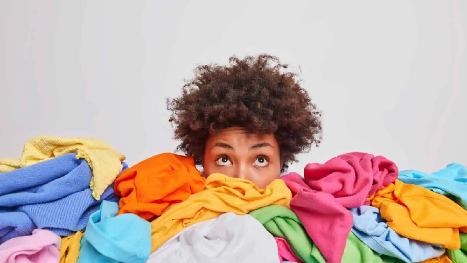 Woman behind pile of cothes