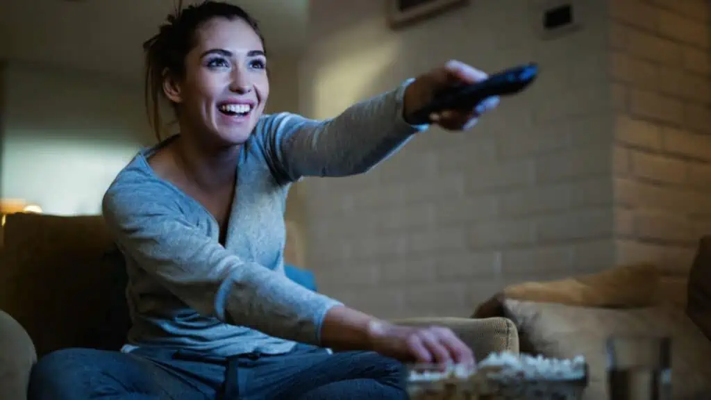 Woman watching tv eating popcorn