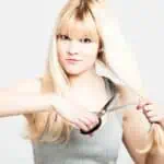 blonde woman cutting her own hair