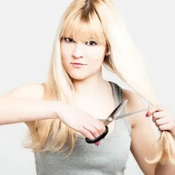 blonde woman cutting her own hair