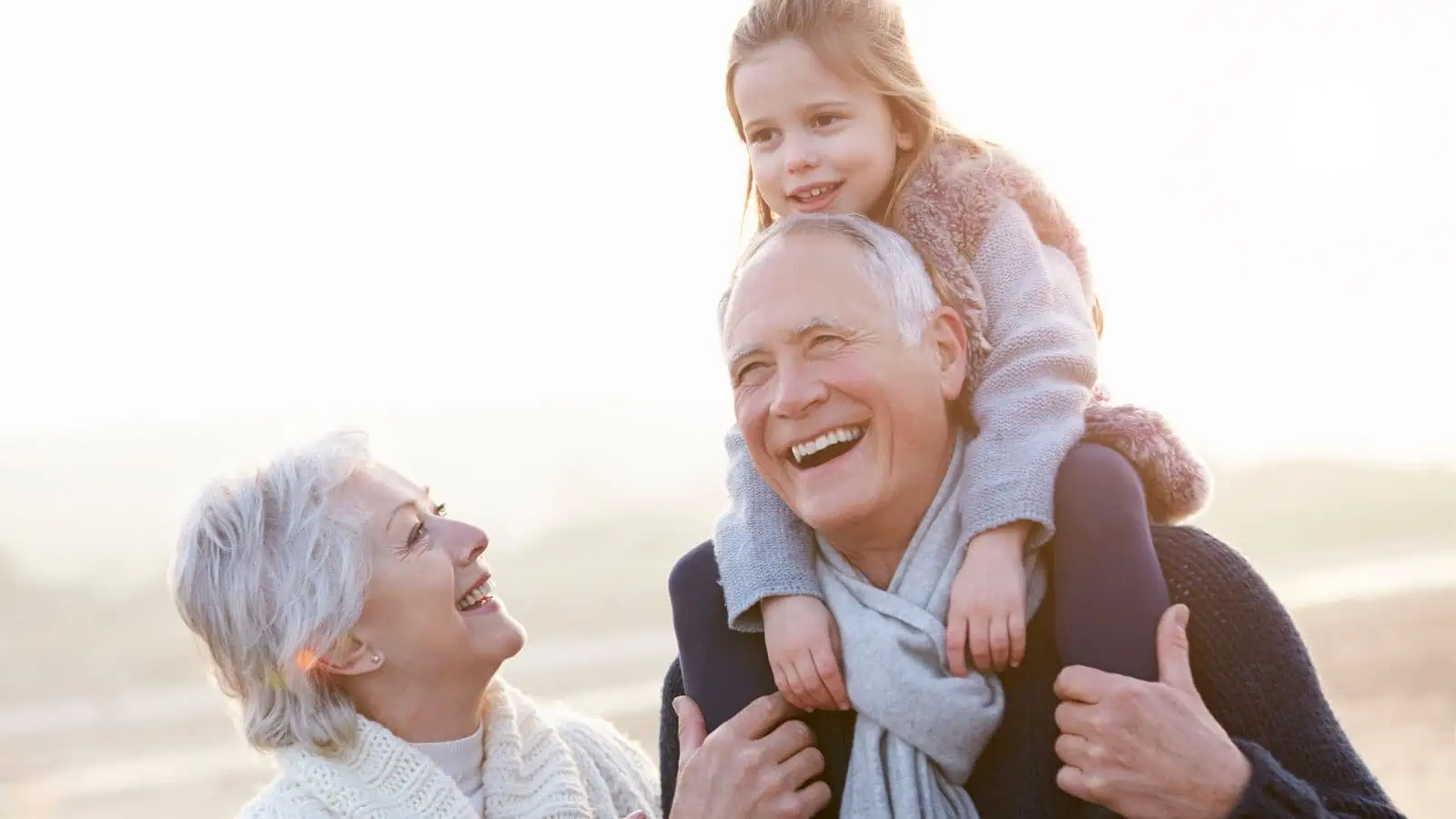 grandparents with granddaughter on shoulders