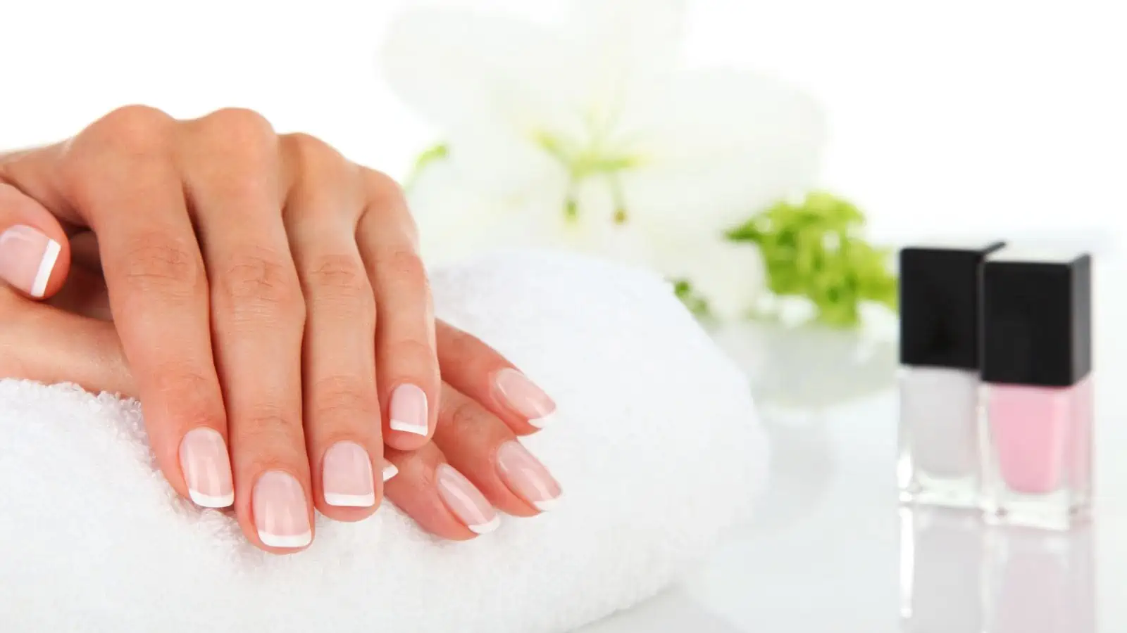 manicured hands on white towel next to nail polish