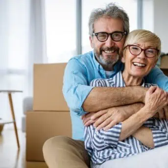 older couple hugging by moving boxes