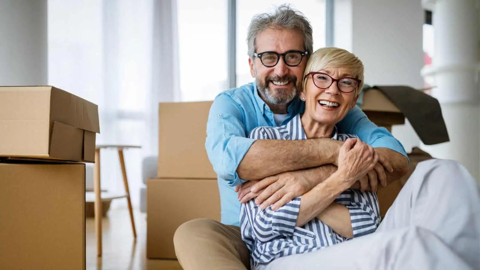 older couple hugging by moving boxes