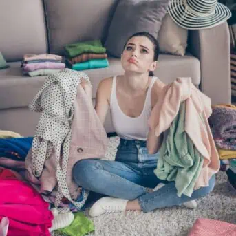 overwhelmed woman surrounded by clothes