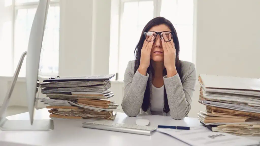 stressed woman surrounded by piles of paper