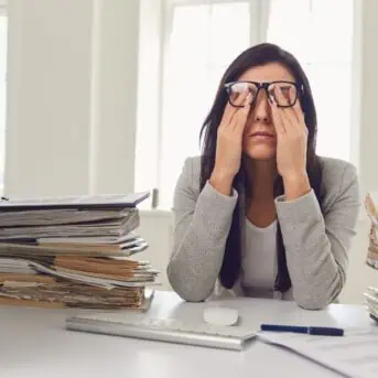 stressed woman surrounded by piles of paper