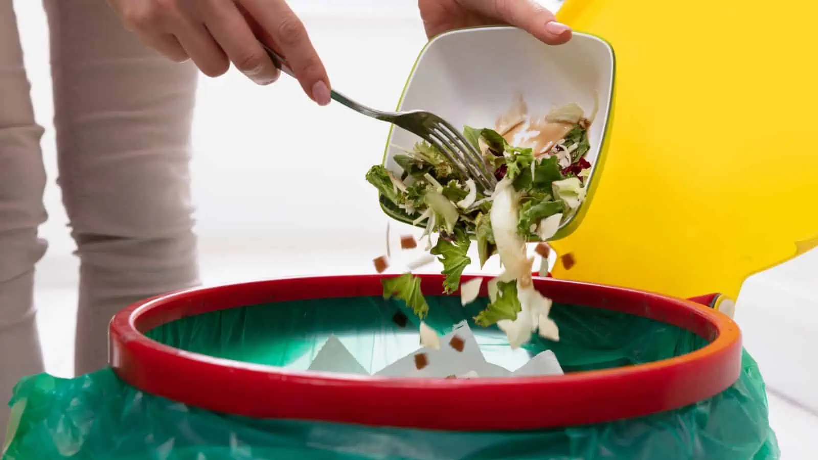 woman throwing out bowl full of salad