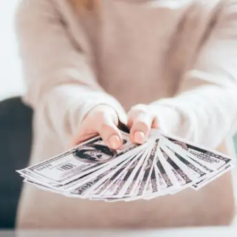 woman with outstretched arms holding money