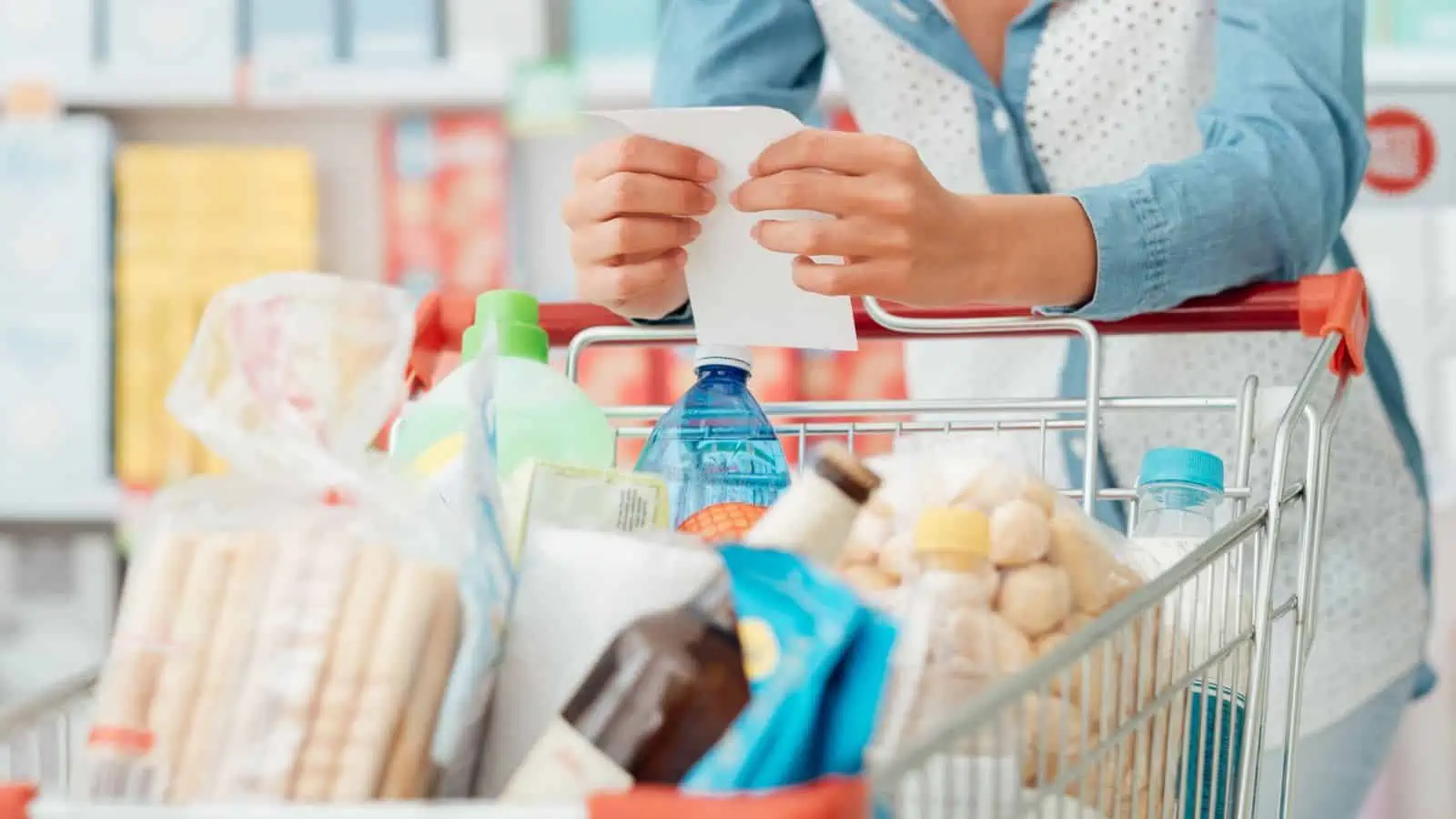 woman with shopping list and cart full of food