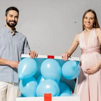 man and woman opening box with blue balloons floating out