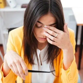 stressed woman sitting at desk with head down