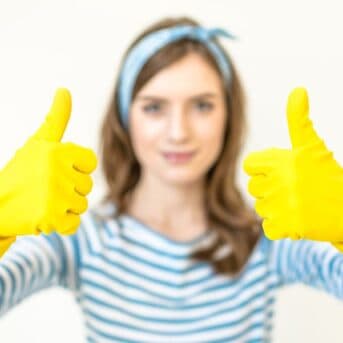 woman with cleaning gloves giving two thumbs up