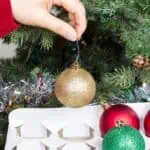 putting Christmas ornaments in organizer in front of a Christmas tree