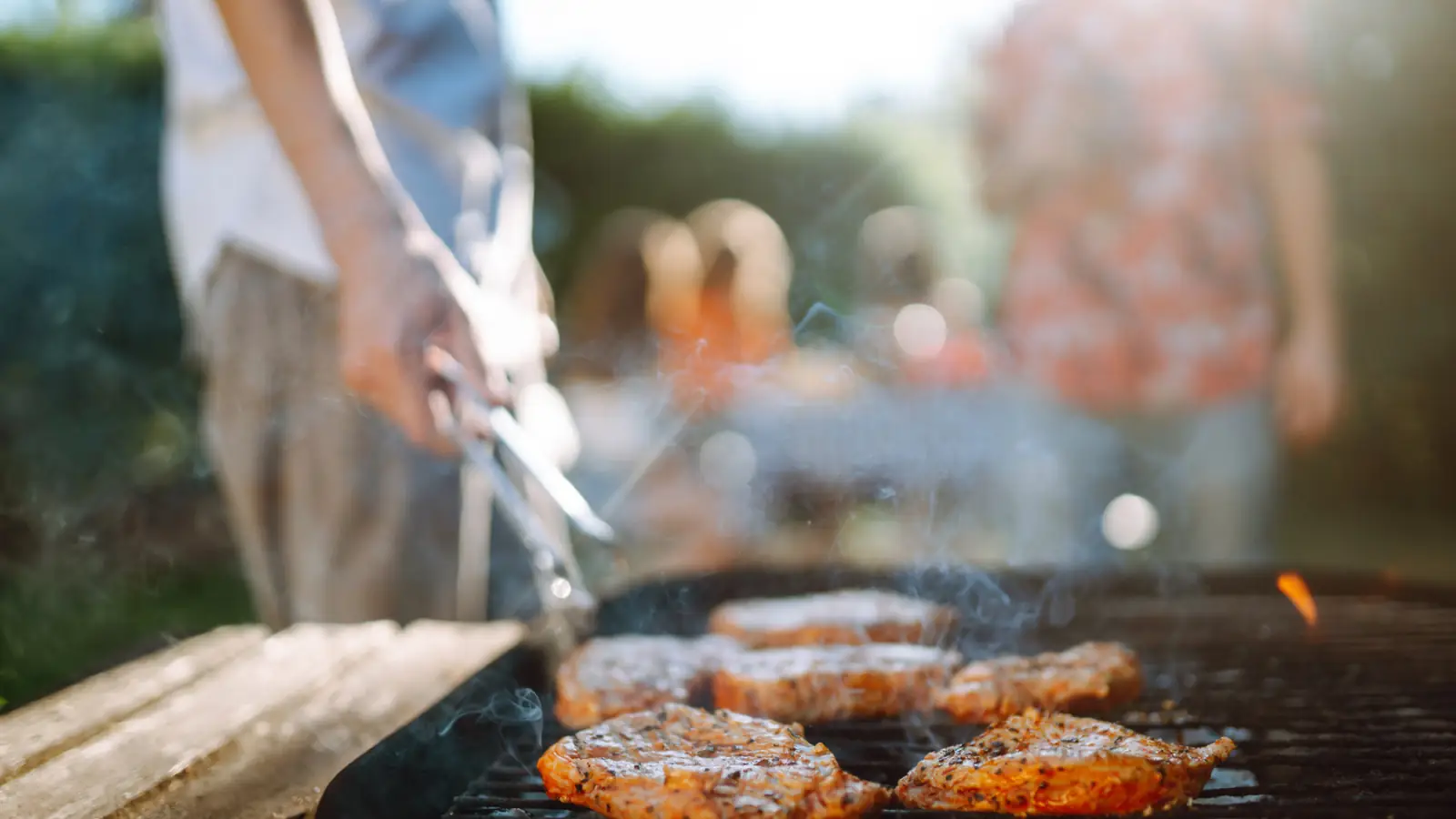 man cooking chicken on a grill people standing around