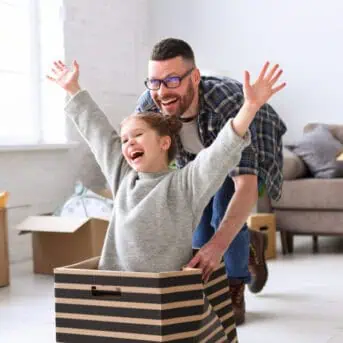 Playful family: father riding kid daughter in box
